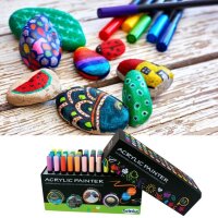 Acrylstifte in Box und bemalte Steine auf Tisch