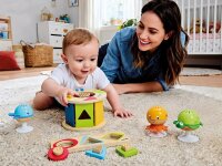 Baby und Erzieherin mit Entdecker-Spielzeug